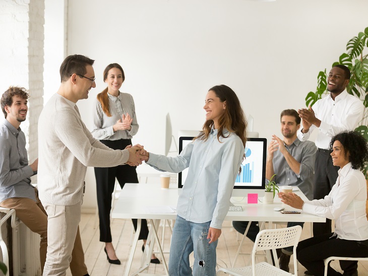 Fiatal dolgozó férfiak és nők egy csoportja világos irodában ünnepel